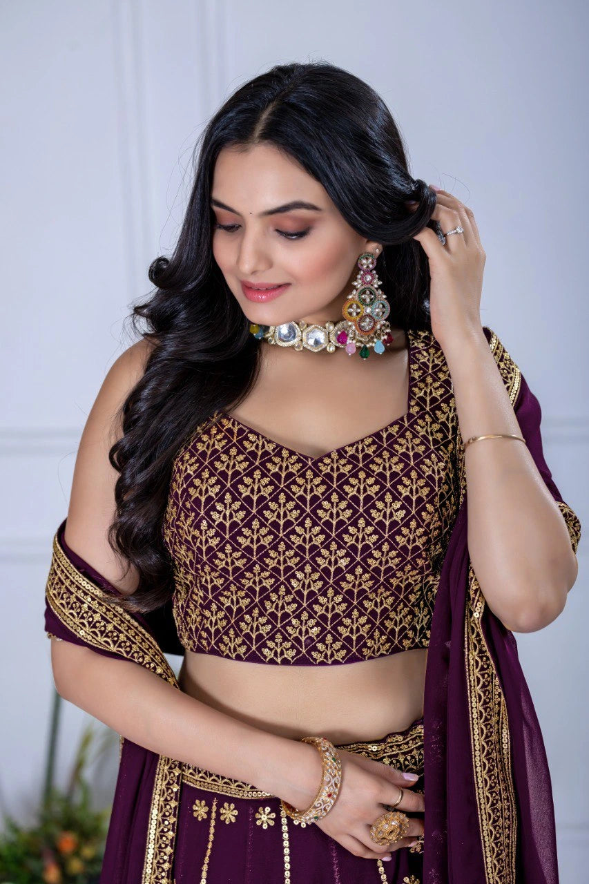 Woman in traditional purple and gold outfit with jewelry against a neutral background